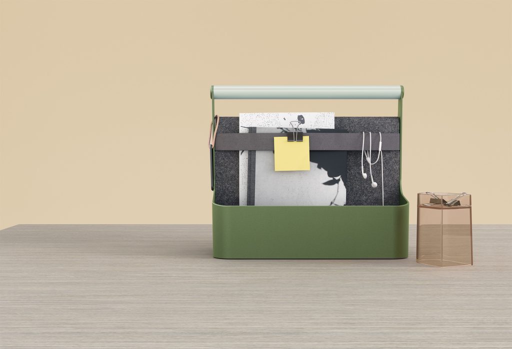 YouMe green toolbox with a verdigris steel handle. It contains a notebook, a post-it notepad, and headphones.