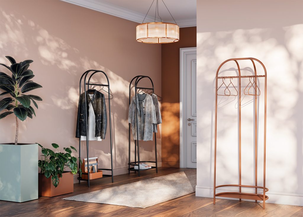 Ambient image of a room with three steel coat racks. Industrial inspiration. The terracotta coat rack in the foreground is empty. The other two, black ones, at the back of the room hold clothes arranged on hangers and objects placed on the lower shelf.