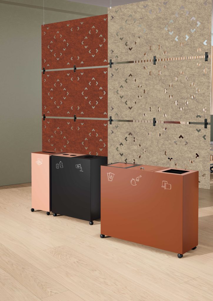 In the foreground of this image are three tall, powder-coated steel recycling bins on casters. Behind them, two openwork acoustic curtains in PET felt hang from the ceiling.