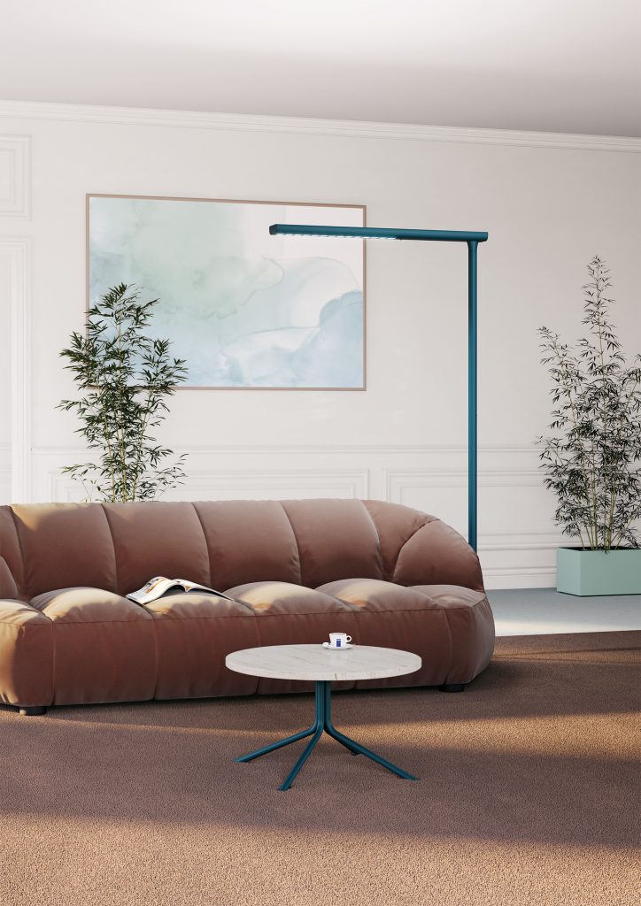 Petrol blue floor lamp positioned at the corner of a modern sofa.